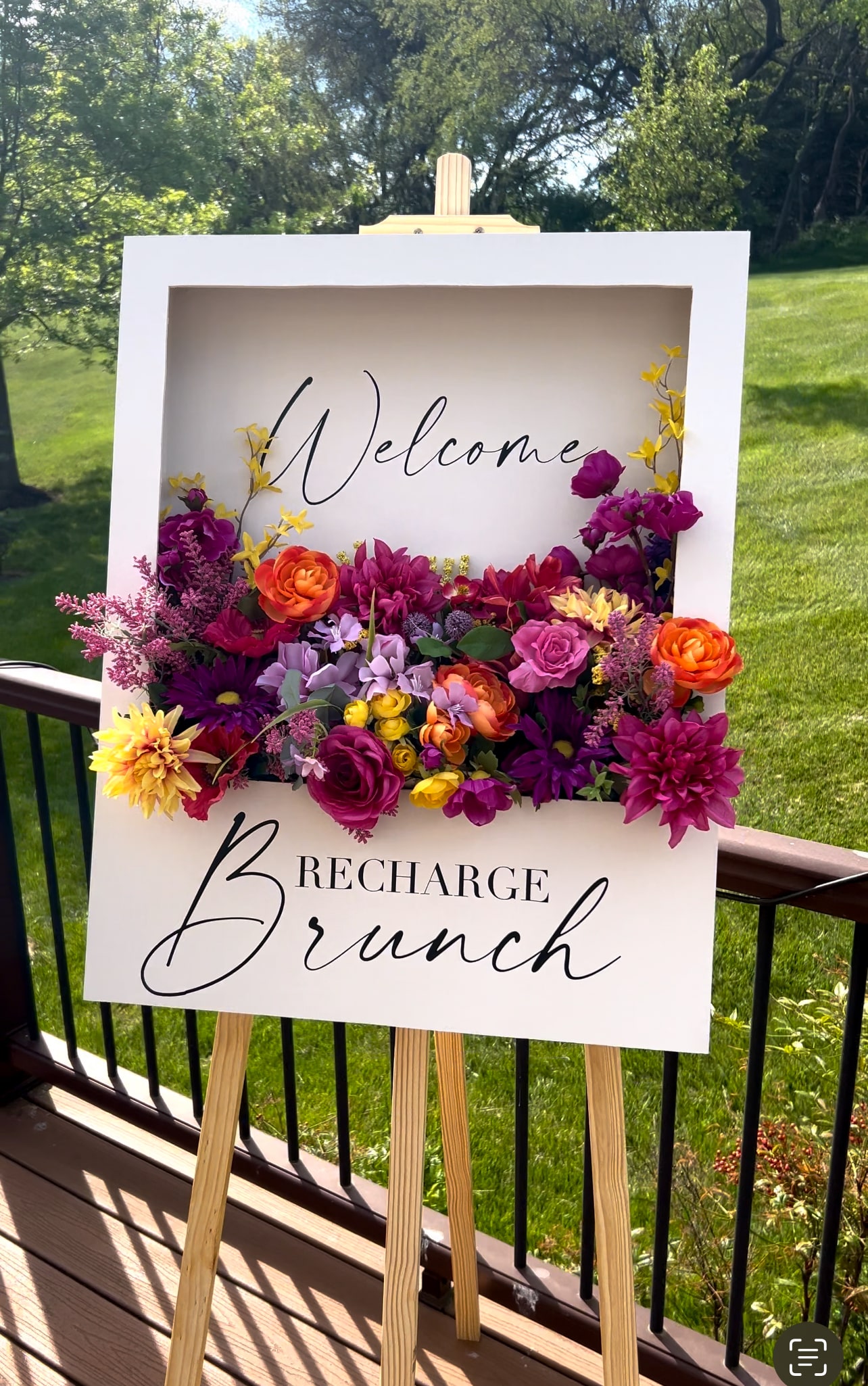 completed flower box welcome sign with purple, orange, and yellow flowers and writing that says welcome.