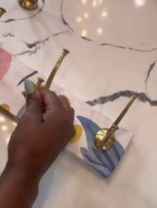 image of hand adding hooks to a board that has been wrapped in wallpaper