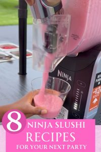 A Ninja Slushi machine dispensing a pink slushie into a cup being held by a hand.