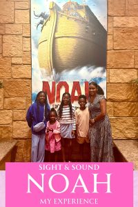 Family standing in front of a Noah sign and the arc.