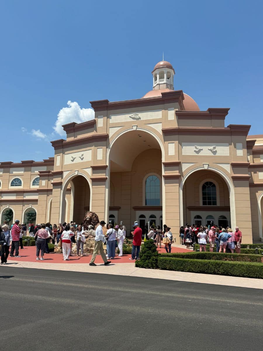 Outside of a tan building with people walking around.
