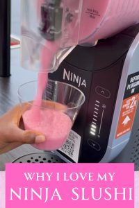 Close up image of Ninja slushi machine being used to put pink slushi into a cup being held by a hand.