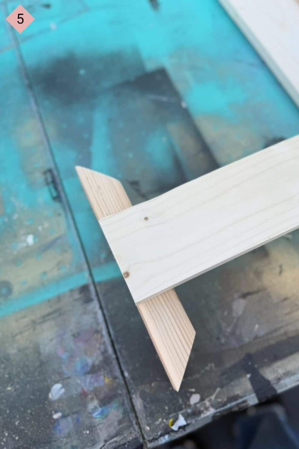 A picture of two boards together in the shape of a "T" on a blue paint stained background.
