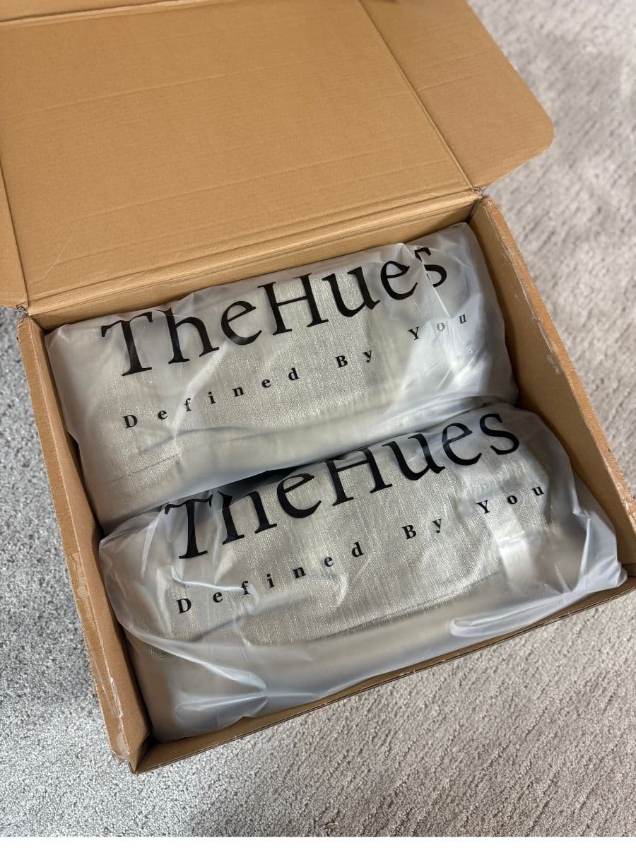 Two curtains in bags that say The Hues Defined by you, both in a box.