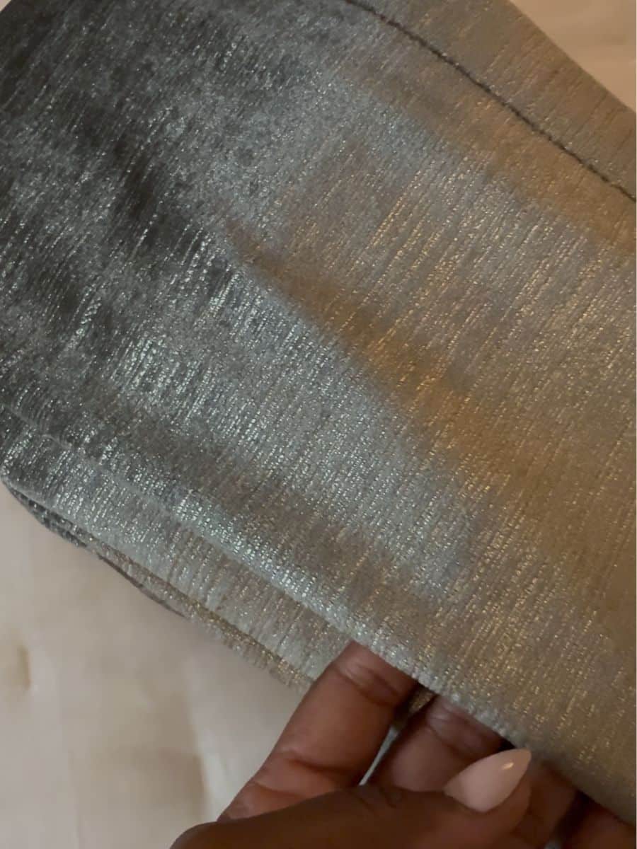 Shimmery curtain fabric with a hand feeling the fabric.